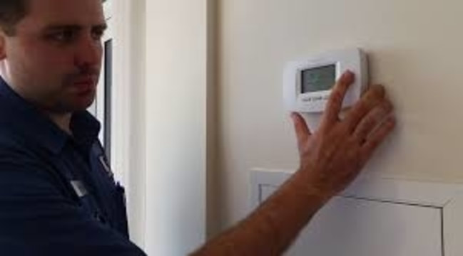 repairman adjusting thermostat
